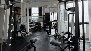 A gym with various exercise equipment, large windows, and a view of the sea. - Hotel Hernandez CTG (Cartagena)