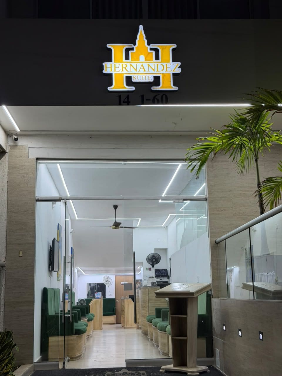 Entrada do hotel Hernandez Suite, com área de recepção, assentos e um balcão visível.