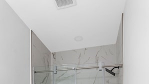 A modern bathroom with a glass-enclosed shower, a white toilet, and a towel rack. - Studio 1 ~ Lovely Apartment, Downtown! (Moncton)
