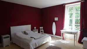 A bedroom with a bed, bedside tables, a lamp, a chair, a table, and a window with curtains. - Beautiful town house for your mini bteak (Cazouls-lès-Béziers)