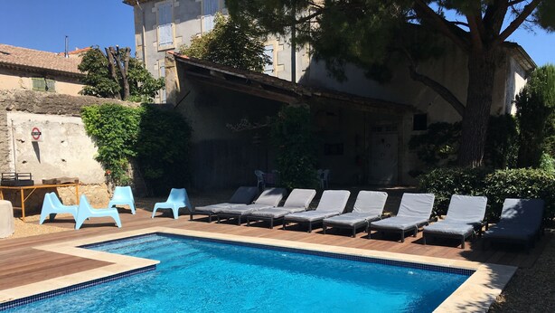 A swimming pool with lounge chairs and a table, surrounded by a stone wall and trees. - Beautiful town house for your mini bteak (Cazouls-lès-Béziers)
