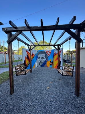 Un columpio de madera con un mural colorido de fondo.