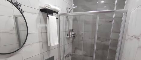Un baño moderno con lavamanos blanco, inodoro y cabina de ducha con mampara de vidrio.