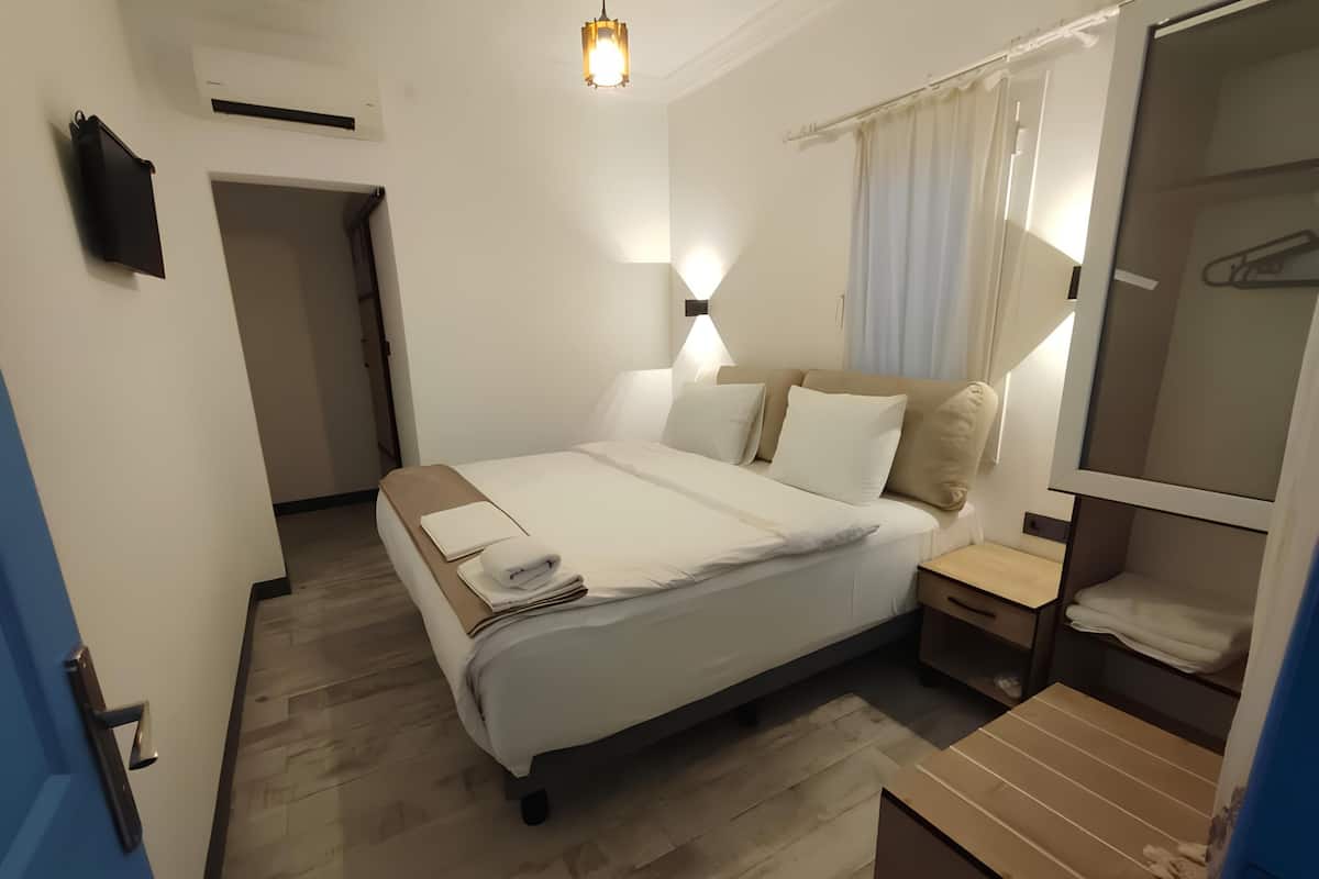A hotel room with a bed, bedside table, and a mirror.