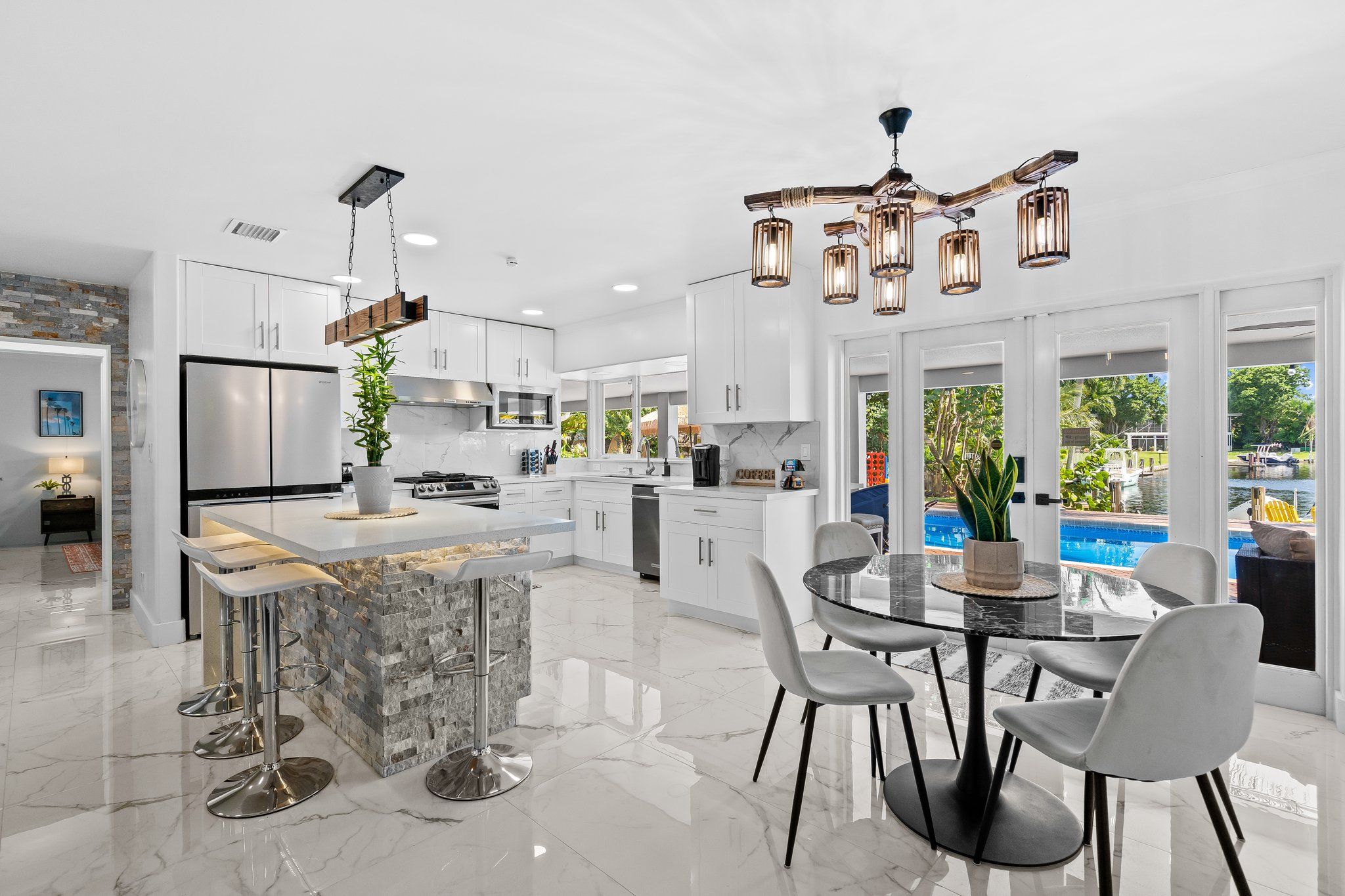 Una cocina moderna con una isla central, electrodomésticos de acero inoxidable y un comedor con una mesa redonda y sillas.