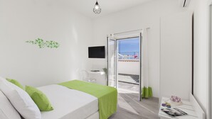 Une chambre moderne avec un lit, un bureau et un balcon offrant une vue agréable.