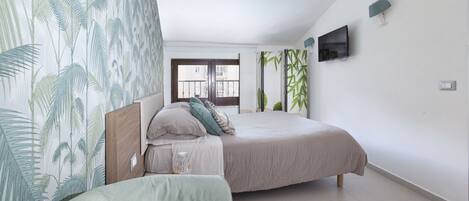 A bedroom with a bed, a nightstand, a lamp, and a window with curtains.