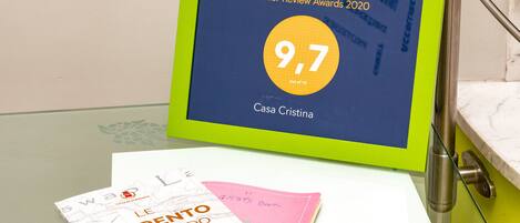 A digital display with a 9.7 rating for Casa Cristina, accompanied by a book titled "Le Sorrento nel mondo" and a pink notebook.