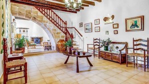 Ein geräumiges Wohnzimmer mit einer Holztreppe, einem Chandelier und verschiedenen gerahmten Bildern an den Wänden.