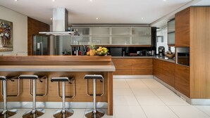 A modern kitchen with a central island, bar stools, and a variety of appliances.