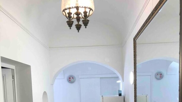 A hallway with a tiled floor, a wooden bench, a large mirror, and a chandelier. - Stunning Fishermans House in Central Fuseta (Olhao)