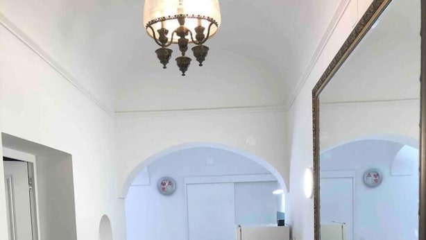 A hallway with a tiled floor, a wooden bench, a large mirror, and a chandelier. - Stunning Fishermans House in Central Fuseta (Olhao)