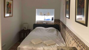 A bedroom with a bed, a nightstand, a lamp, and two framed pictures on the wall. - Stunning Fishermans House in Central Fuseta (Olhao)