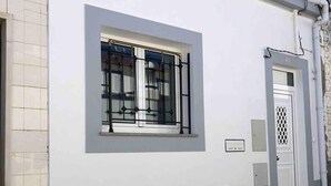 A building with a large window, a door, and several electrical boxes on the wall. - Stunning Fishermans House in Central Fuseta (Olhao)
