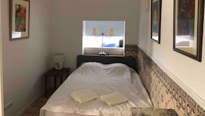 A bedroom with a bed, a nightstand, a lamp, and two framed pictures on the wall. - Stunning Fishermans House in Central Fuseta (Olhao)