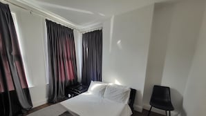Une chambre à coucher avec un lit, une chaise et une valise.
