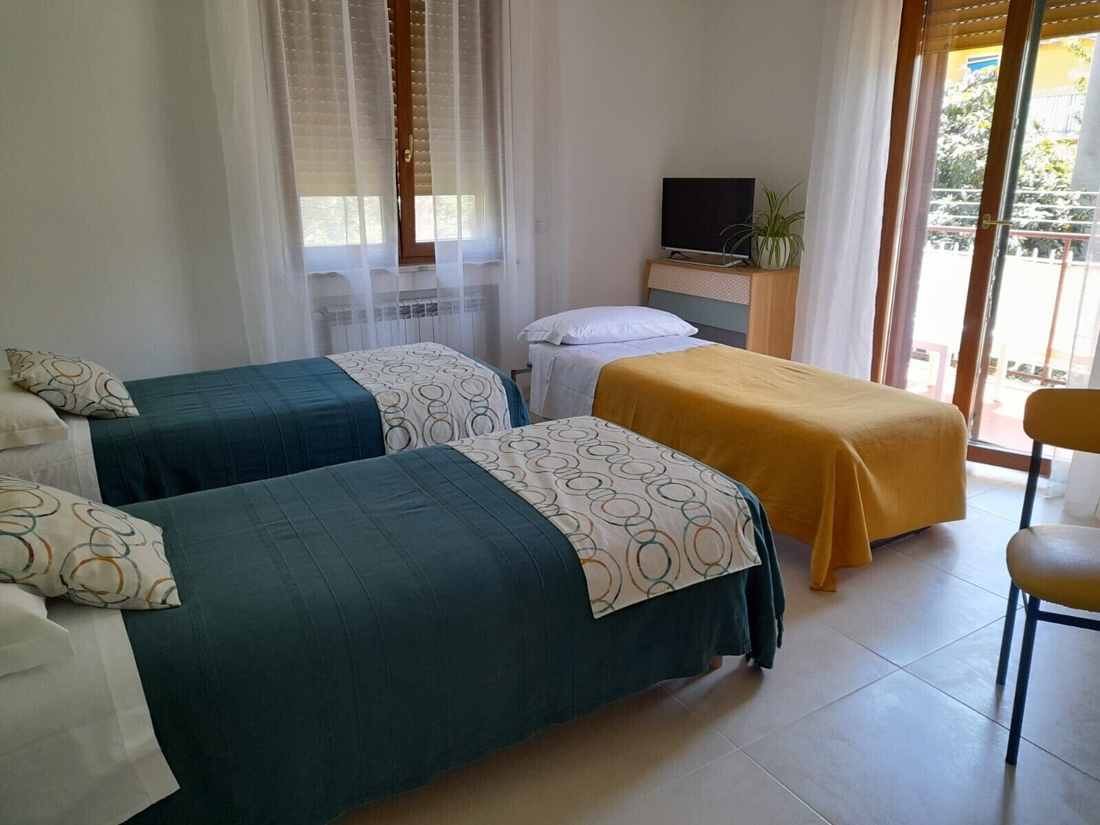 Une chambre d’hôtel avec deux lits, une télévision et un balcon avec vue.