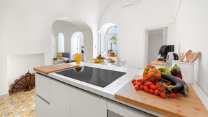 Eine moderne Küche mit einer großen Kochinsel, weißen Schränken und Blick durch einen Bogen in einen Essbereich.