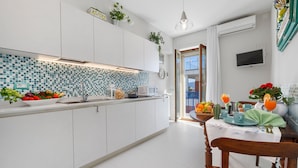 A modern kitchen with white cabinets, a tiled backsplash, and a dining area with a table set for two. - Estate4home - Esé (Sorrento)