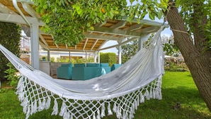 A hammock under a pergola with a view of a garden and outdoor seating. - Resort Ravenna (Massa Lubrense)