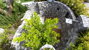 A stone-built structure with a wooden door, surrounded by greenery and a stone wall. - Resort Ravenna (Massa Lubrense)