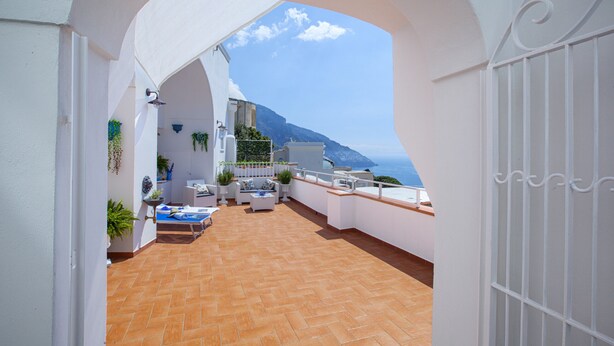 Une terrasse sur le toit offrant une vue sur la mer, avec des murs blancs et un sol carrelé.