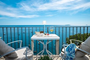 A balcony with a table set for two, overlooking a body of water with boats.