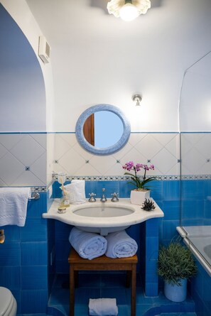 A bathroom with a sink, mirror, and blue tiles.