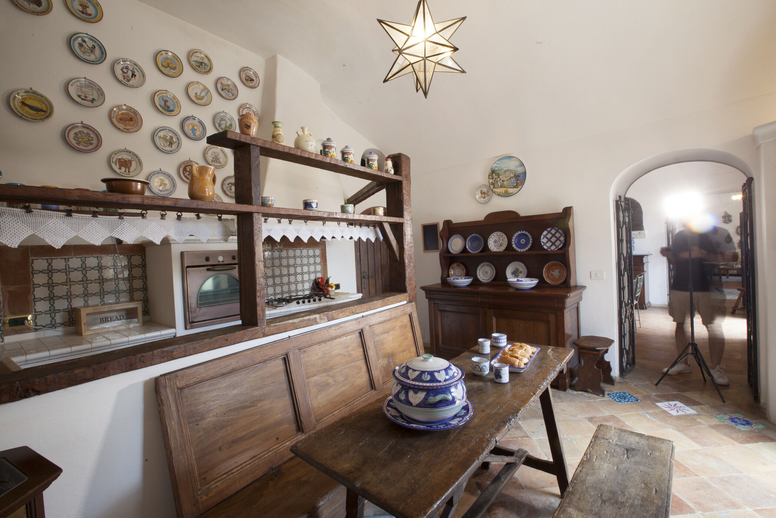 Una cocina rústica con estantes de madera, una mesa de madera y una variedad de vajilla y cerámica.