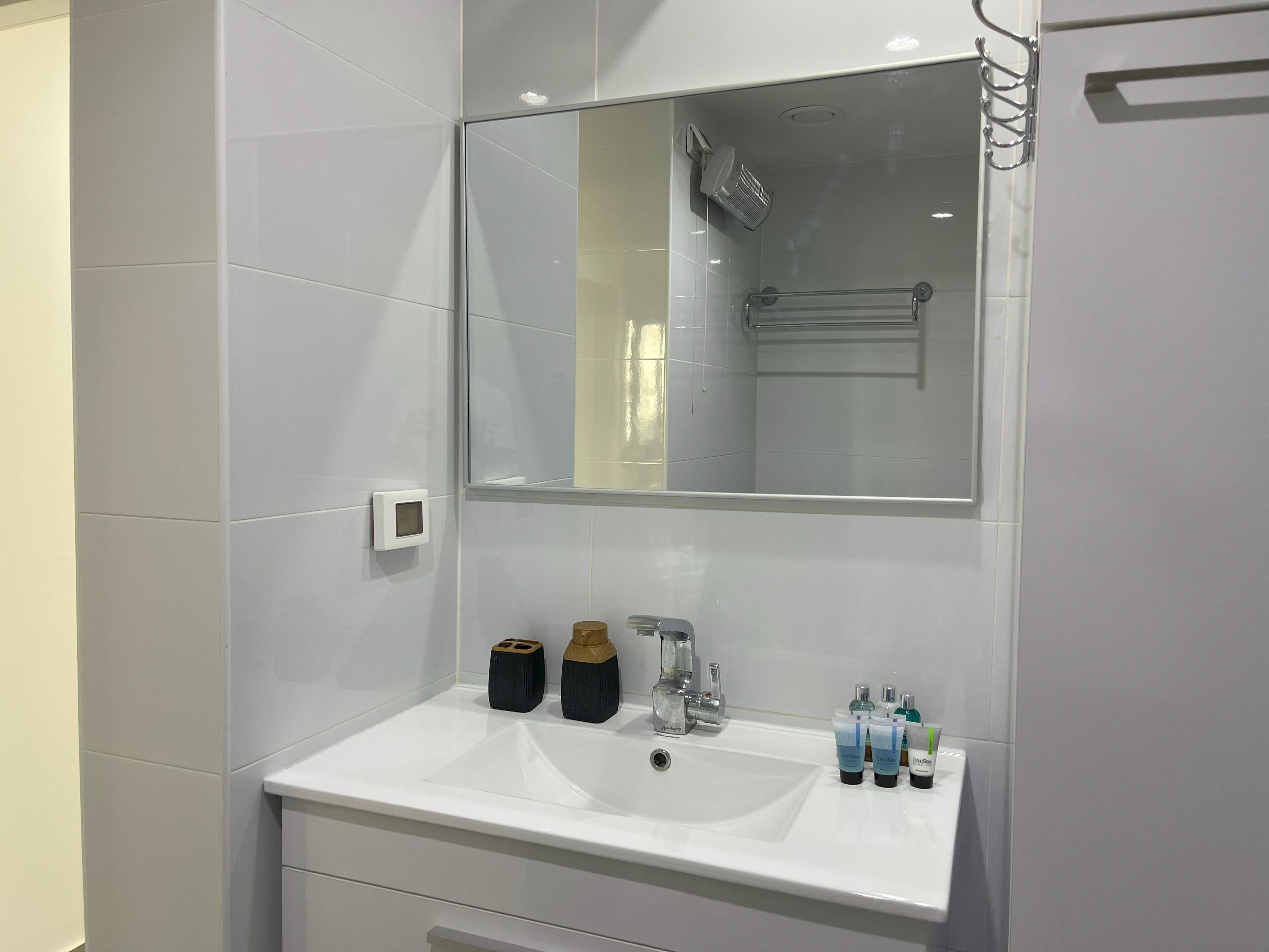 Uma casa de banho moderna com uma pia branca, um espelho e um chuveiro.