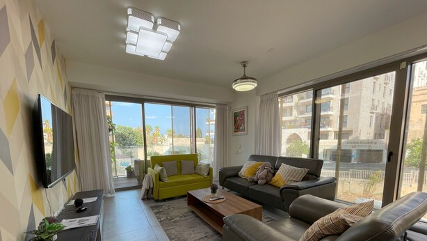 A modern living room with a green sofa, a grey sofa, a coffee table, and a TV on a stand. - AirTLV - Luxury Apartment Port of Jaffa (Tel Aviv)
