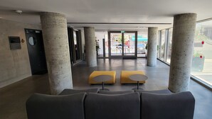 A modern lobby with concrete pillars, a reception desk, and a glass entrance. - AirTLV - Luxury Apartment Port of Jaffa (Tel Aviv)