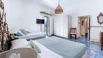 A hotel room with two beds, a television, a chair, and a view of the outdoors.