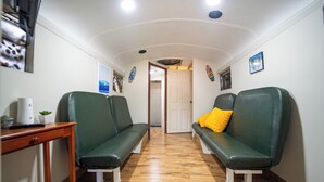 A hallway with two green leather sofas, a wooden table with a plant, and a door at the end.