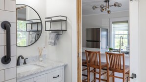 A modern bathroom with white cabinetry, a marble countertop, and a wooden floor. - Cozy 1+ Bedroom Haven with Charm and is a block from downtown! (Manistee)