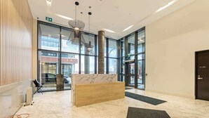 A modern lobby with a marble floor, a reception desk, and large windows. - Union Towers Condo with City Views and Patio (Kitchener)