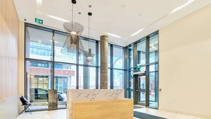 Un lobby moderno con una recepción de mármol, ventanas amplias y una lámpara colgante original.