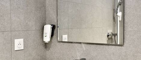 Un baño con lavamanos blanco, un espejo y dispensador de jabón de mano.