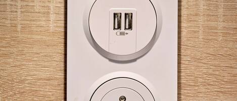 Toma de corriente empotrada en la pared, con dos puertos USB y un enchufe estándar de tres clavijas.