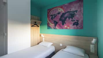 A room with two beds, a wooden headboard, a world map painting, a light switch, and a hanging light fixture.