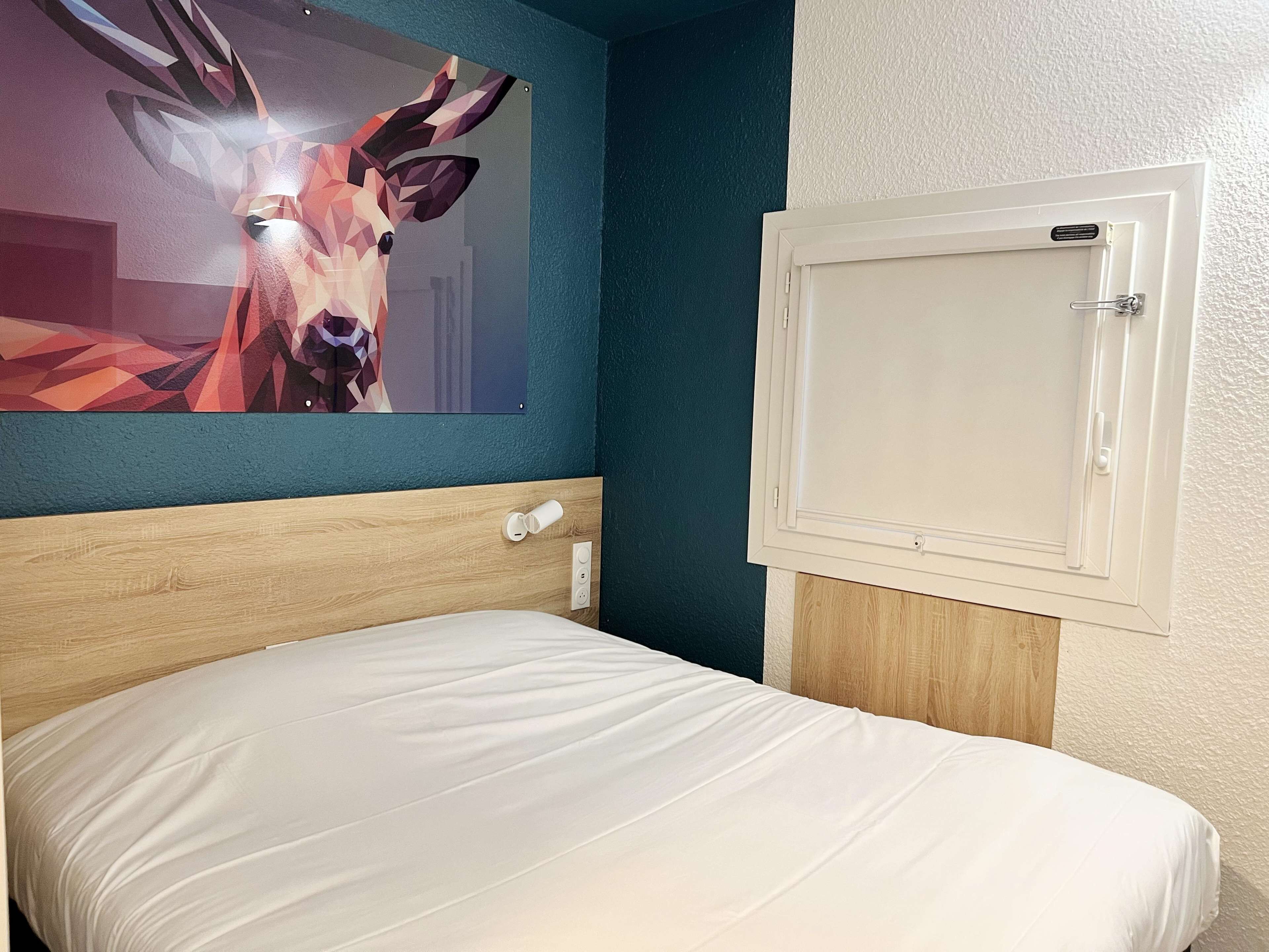 Une chambre d’hôtel avec un lit, un téléviseur fixé au mur et une porte dotée d’une poignée.