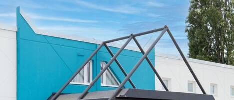 Un edificio moderno con fachada azul, estructura de vidrio y estructura metálica.
