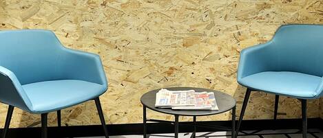 A room with two blue chairs, a small table with a magazine, and a sign that reads "ESPACE COWORKING".