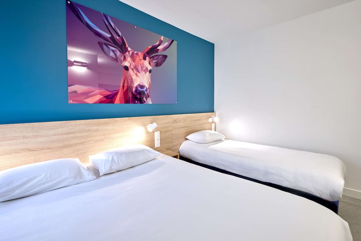 A hotel room with two beds, a wooden headboard, and a large abstract painting on the wall.