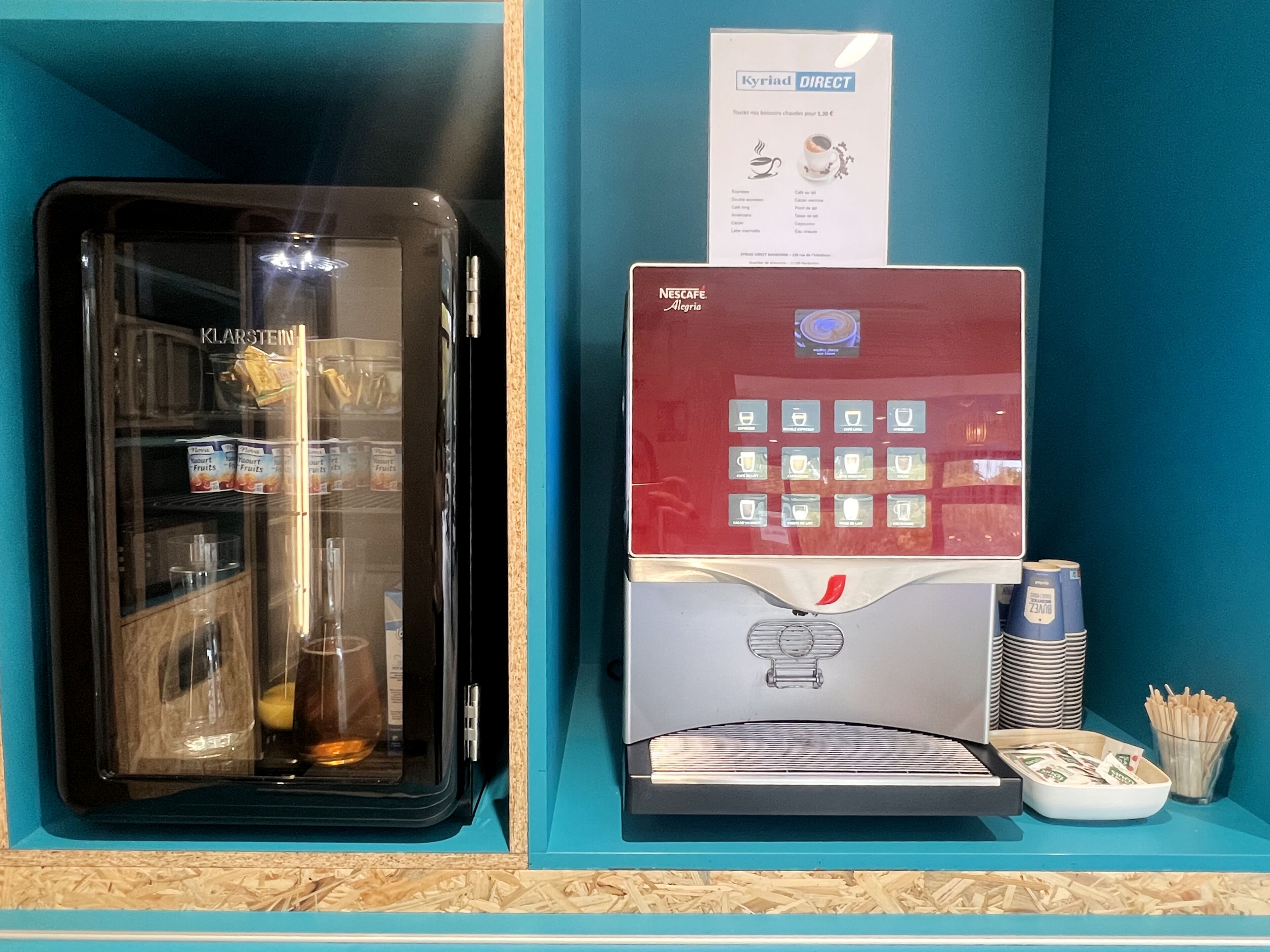 A coffee machine with a menu screen and a glass display case with yogurt and fruits.