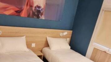 A room with two beds, a wooden headboard, and a wall-mounted TV displaying a cow.