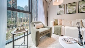 A modern living room with a large window, a sofa, a coffee table, and abstract art on the wall. - Sumptuous 1BR at Act One Act Two Tower 1 Downtown Dubai by Deluxe Holiday Homes (Dubai)