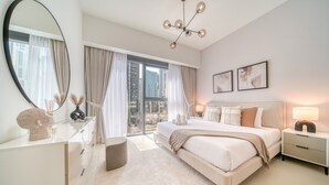 A modern bedroom with a large bed, a round mirror, a nightstand, and a view of the city. - Sumptuous 1BR at Act One Act Two Tower 1 Downtown Dubai by Deluxe Holiday Homes (Dubai)