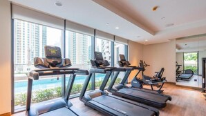 A gym with treadmills and stationary bikes, large windows, and a view of high-rise buildings. - Sumptuous 1BR at Act One Act Two Tower 1 Downtown Dubai by Deluxe Holiday Homes (Dubai)
