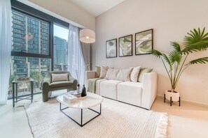 A modern living room with a sofa, armchair, coffee table, and a large window with a city view.